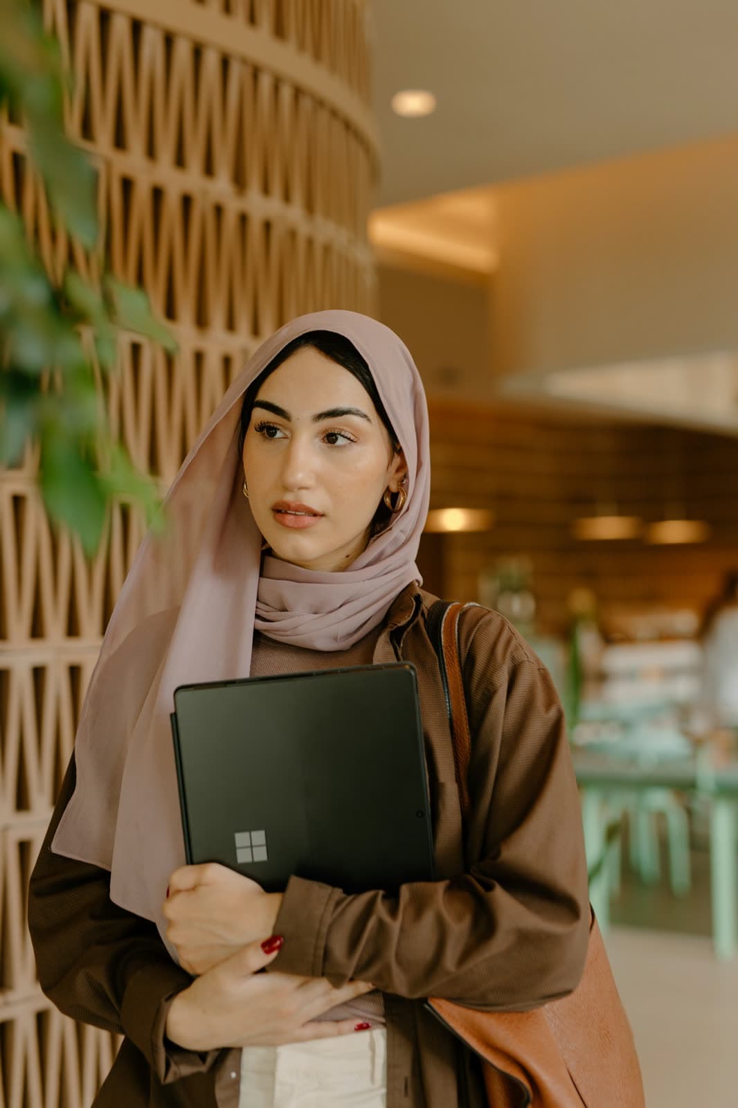 طالبة في الحرم الجامعي تحمل حاسوبها